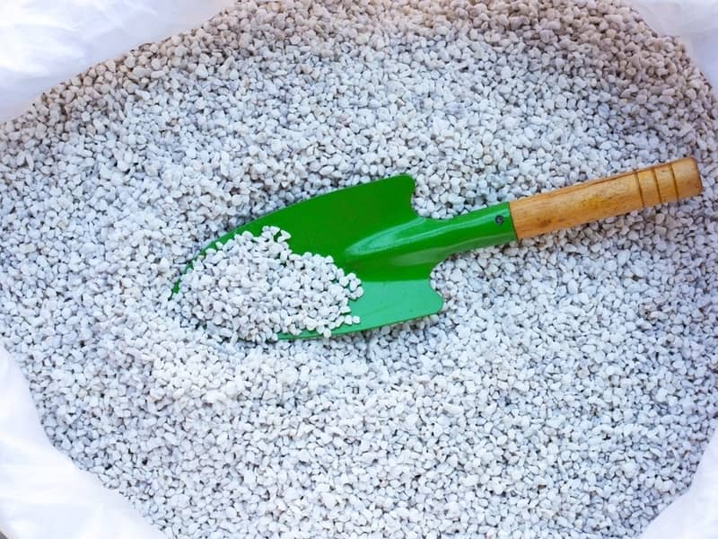 a sack full of perlites with small green plant shovel